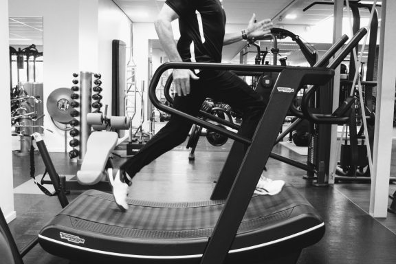Een hardloper op een loopband in een sportschool, zwart-wit afbeelding.